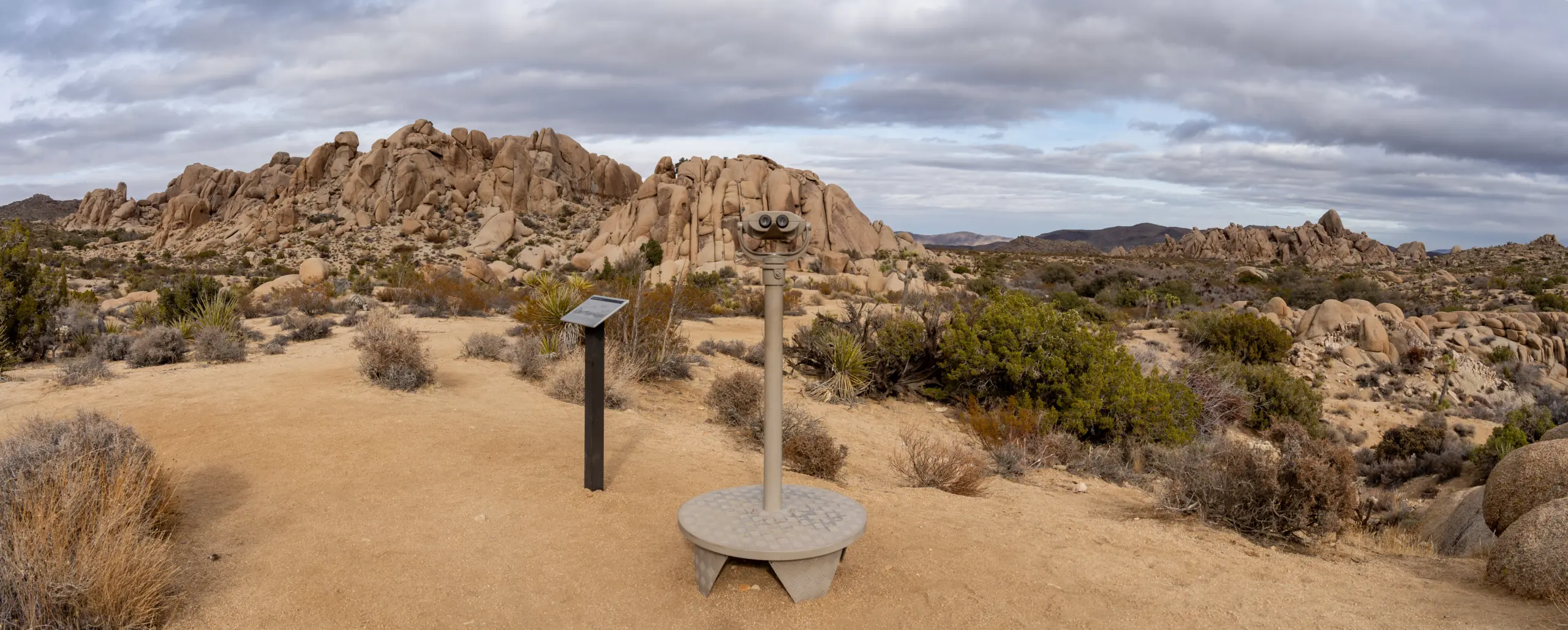 Desert walking trail with a viewing scope and low shrubs