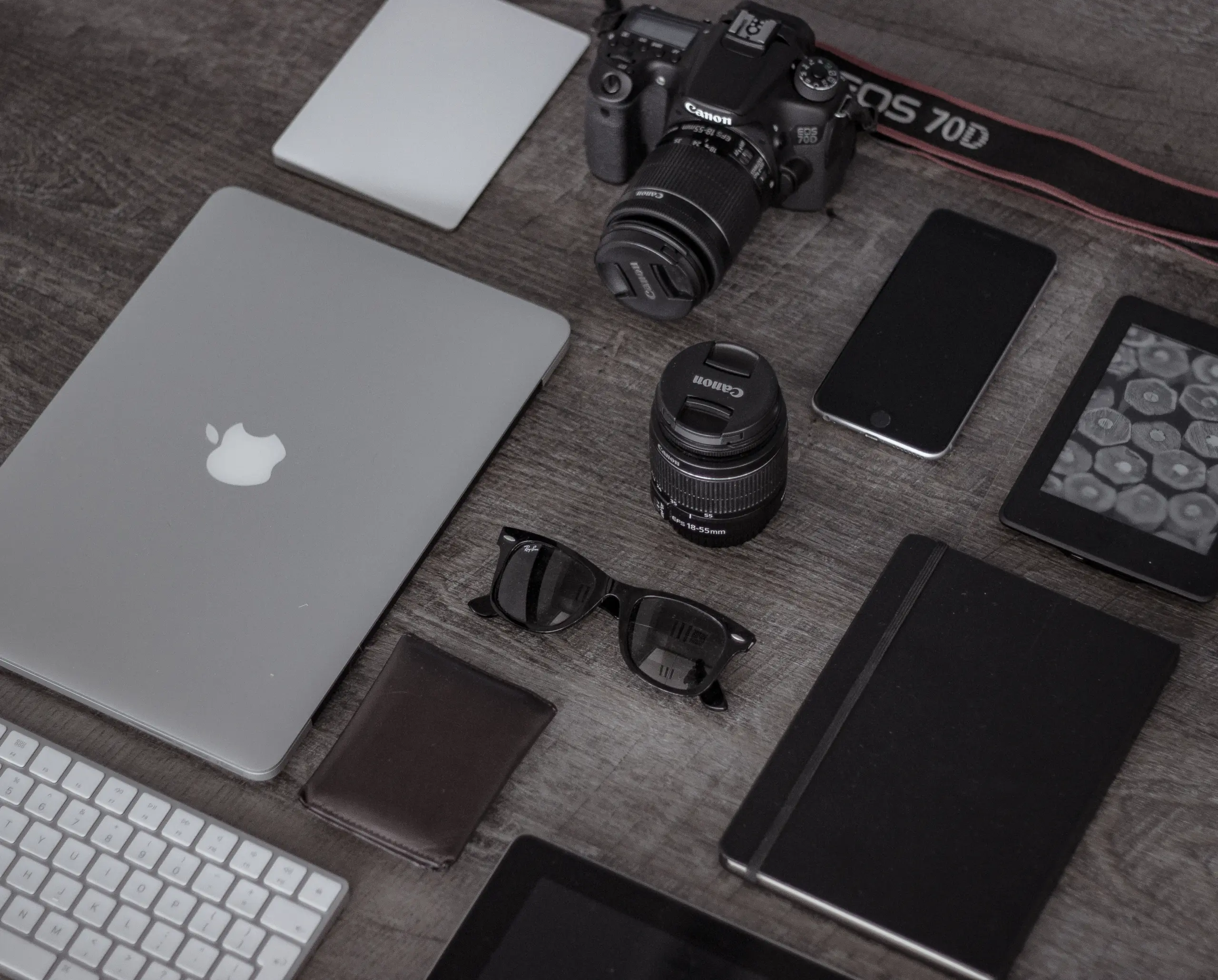 Laptop, phone, camera, and notebook arranged on a desk